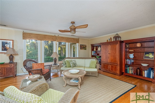 living room featuring ceiling fan, light hardwood / wood-style floors, ornamental molding, and a textured ceiling