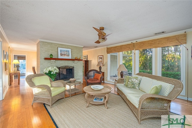 living room with a fireplace, a textured ceiling, and light hardwood / wood-style flooring