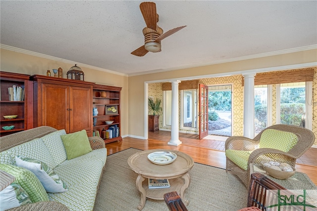 living room featuring decorative columns, ceiling fan, light hardwood / wood-style flooring, and ornamental molding