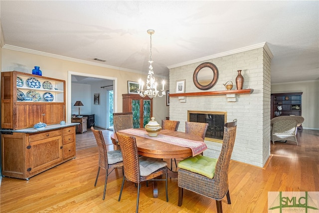 dining room featuring a fireplace, light hardwood / wood-style floors, a notable chandelier, and ornamental molding