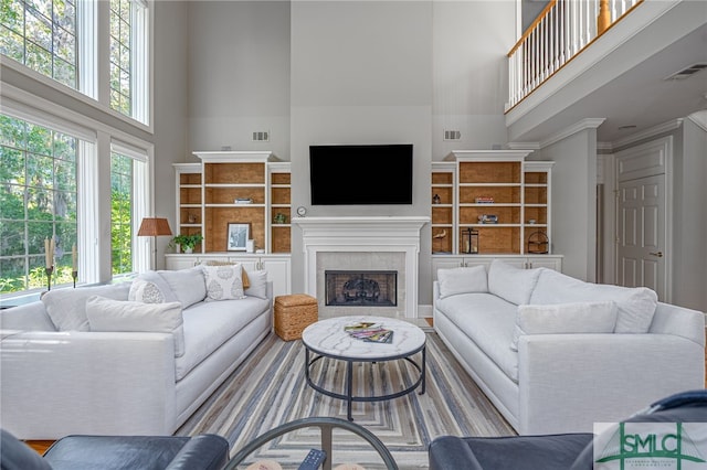 living room featuring a tile fireplace, a towering ceiling, and a wealth of natural light