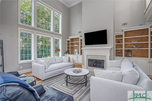 living room with a high ceiling, light hardwood / wood-style flooring, plenty of natural light, and ornamental molding