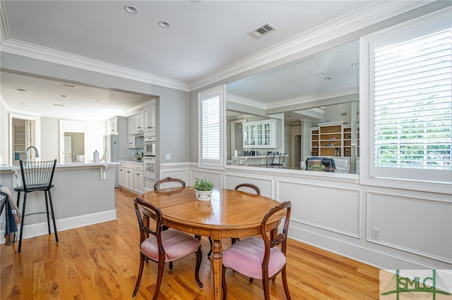 dining area featuring plenty of natural light, ornamental molding, and light hardwood / wood-style flooring