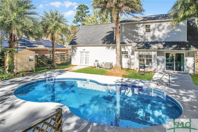 outdoor pool with fence, central AC, and a patio