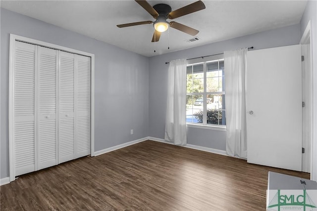 unfurnished bedroom featuring dark wood-type flooring, a closet, and ceiling fan