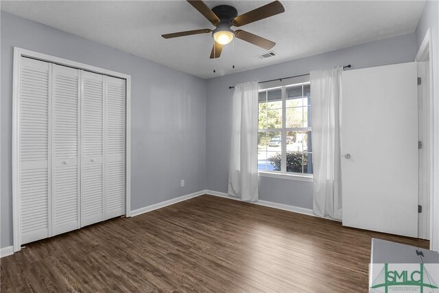 unfurnished bedroom with dark wood-type flooring, a closet, visible vents, and baseboards