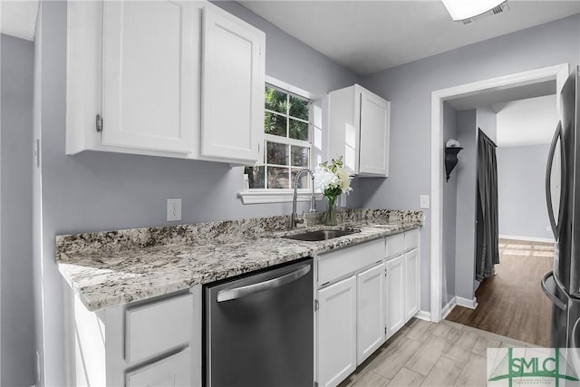 kitchen with stainless steel appliances, light stone countertops, sink, and white cabinets