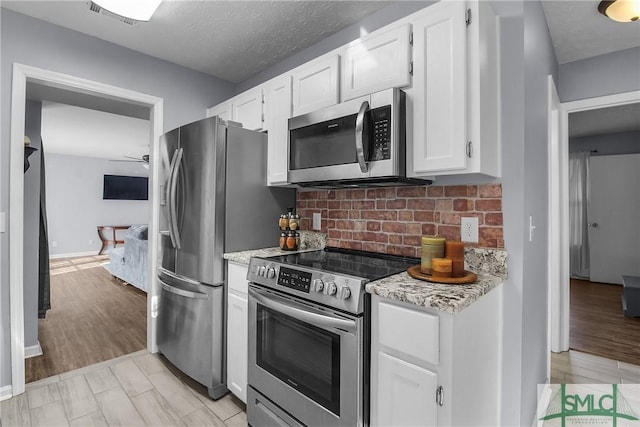 kitchen with white cabinetry, light stone counters, tasteful backsplash, and appliances with stainless steel finishes