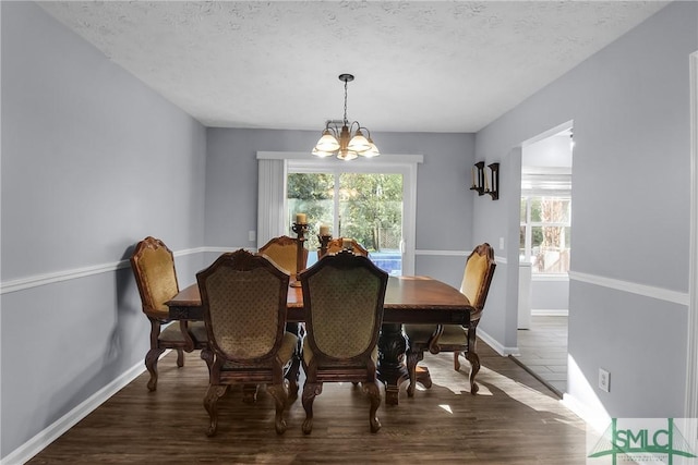 dining area with dark hardwood / wood-style floors, a textured ceiling, and a notable chandelier