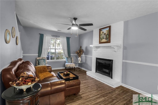 living room featuring ceiling fan, hardwood / wood-style floors, and a brick fireplace