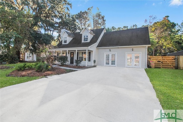 cape cod-style house with a front yard, covered porch, and french doors