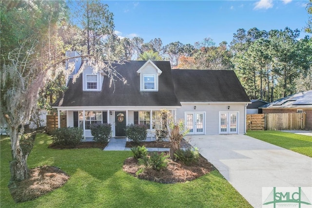 new england style home featuring driveway, fence, a front lawn, and french doors