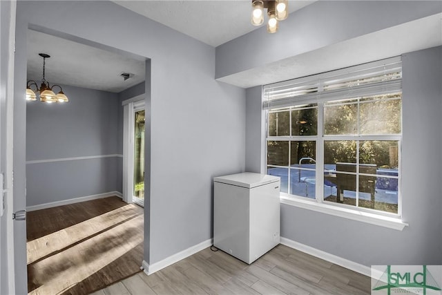 interior space with light wood finished floors, baseboards, and a chandelier