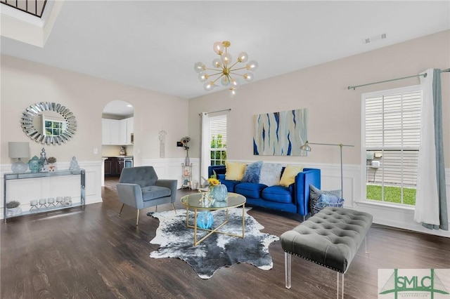 living room with dark hardwood / wood-style floors, an inviting chandelier, and plenty of natural light