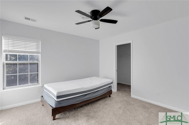 bedroom with ceiling fan, a closet, light colored carpet, and a spacious closet