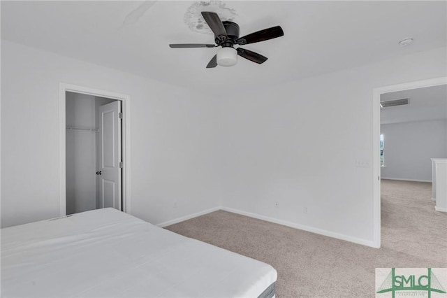 bedroom with ceiling fan, a closet, a spacious closet, and light carpet