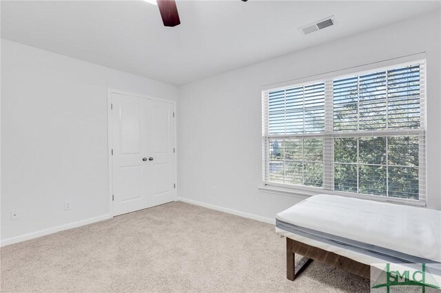 interior space featuring light carpet, ceiling fan, and a healthy amount of sunlight