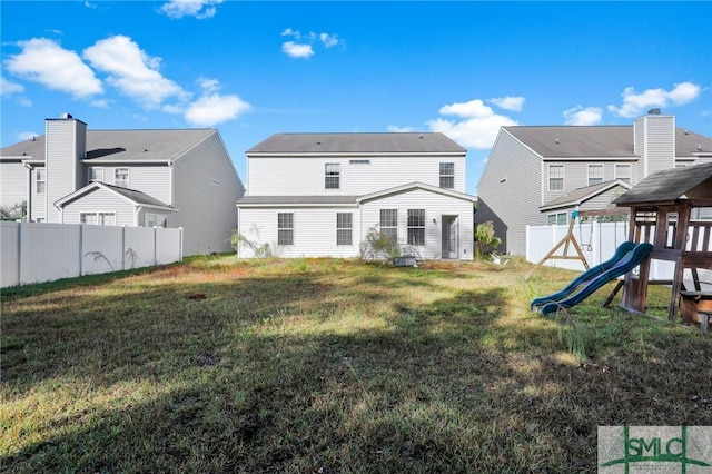 rear view of property with a playground and a yard