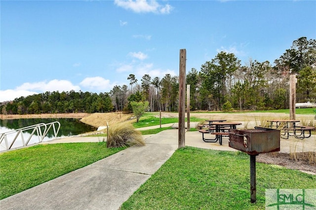 view of home's community with a lawn, a patio area, and a water view