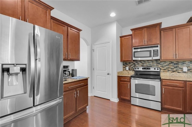 kitchen with light stone countertops, decorative backsplash, stainless steel appliances, and light hardwood / wood-style flooring