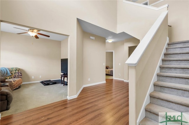 stairway featuring hardwood / wood-style flooring, ceiling fan, and a towering ceiling