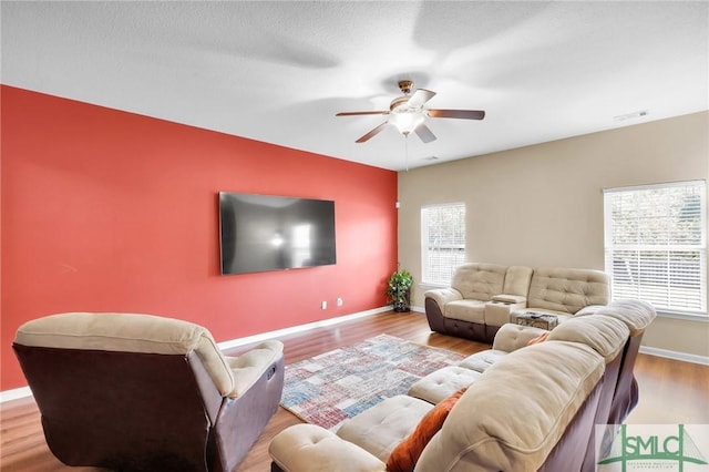 living room with light hardwood / wood-style flooring, ceiling fan, and a healthy amount of sunlight