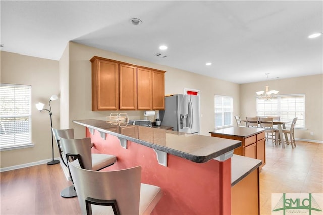 kitchen with pendant lighting, a kitchen breakfast bar, stainless steel fridge, a notable chandelier, and kitchen peninsula