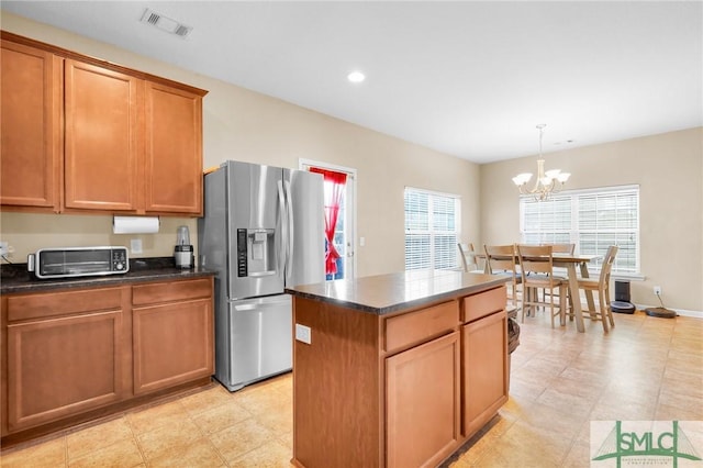 kitchen featuring a center island, stainless steel fridge, pendant lighting, and an inviting chandelier