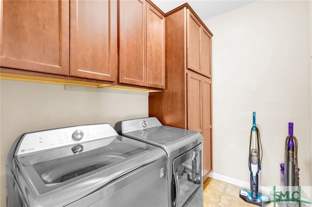 laundry area with washer and dryer, light tile patterned floors, and cabinets