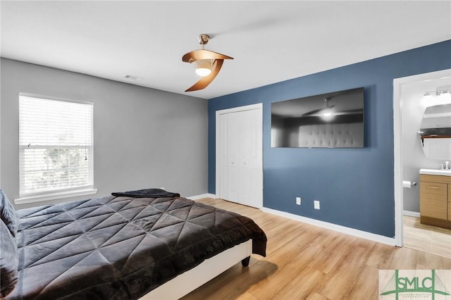 bedroom with ensuite bathroom, ceiling fan, light hardwood / wood-style floors, and a closet