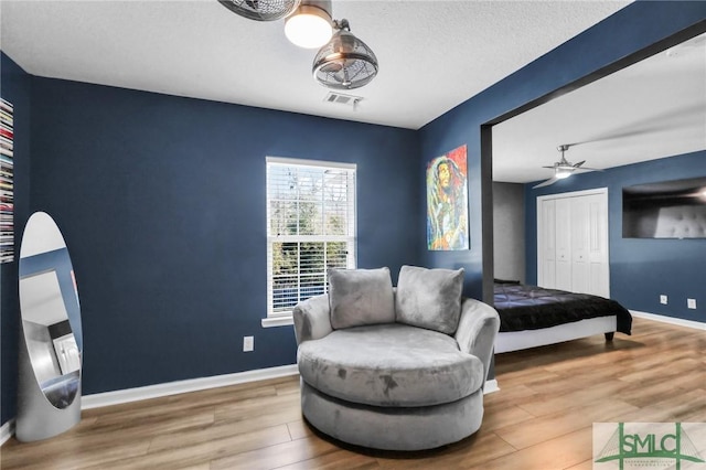 bedroom featuring hardwood / wood-style floors, ceiling fan, a textured ceiling, and a closet