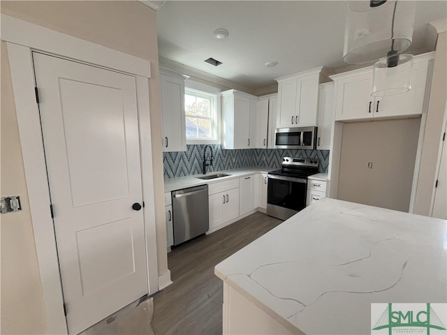 kitchen with sink, hanging light fixtures, light stone countertops, white cabinetry, and stainless steel appliances