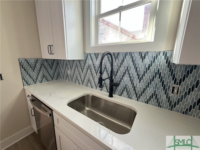 kitchen featuring white cabinets, tasteful backsplash, stainless steel dishwasher, and sink