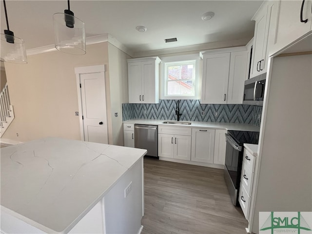 kitchen with tasteful backsplash, stainless steel appliances, sink, decorative light fixtures, and white cabinets