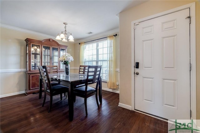 dining room featuring dark hardwood / wood-style floors, an inviting chandelier, and crown molding