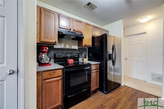 kitchen with black appliances, light wood-type flooring, and tasteful backsplash