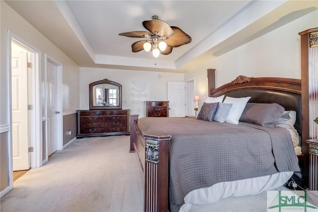 bedroom with a tray ceiling, ceiling fan, and light colored carpet