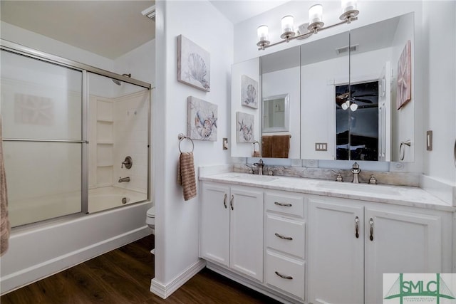 full bathroom featuring vanity, combined bath / shower with glass door, ceiling fan, toilet, and wood-type flooring