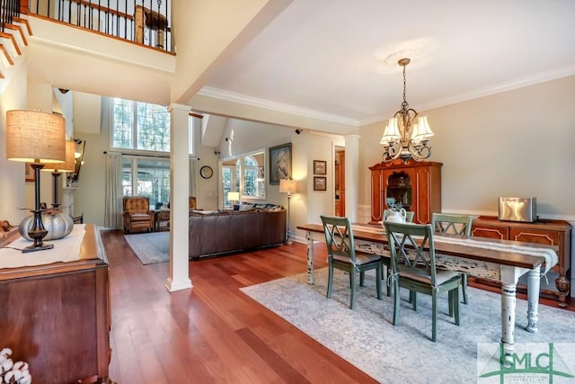 dining area featuring ornamental molding, dark hardwood / wood-style flooring, decorative columns, and a notable chandelier