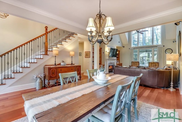 dining space featuring hardwood / wood-style flooring, ornamental molding, and ceiling fan with notable chandelier