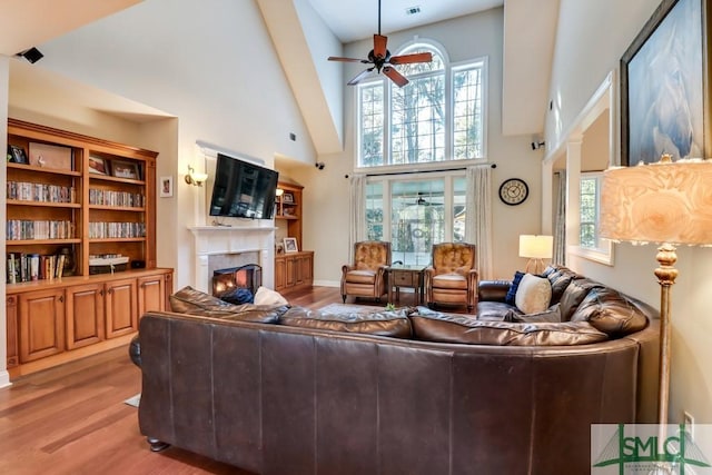 living room with high vaulted ceiling, ceiling fan, and light hardwood / wood-style flooring