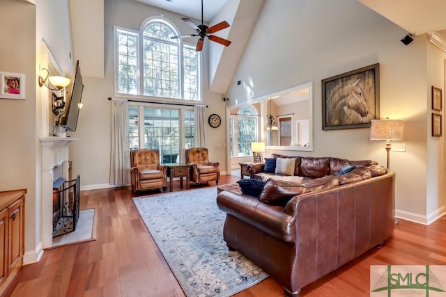 living room featuring hardwood / wood-style flooring, ceiling fan, and high vaulted ceiling