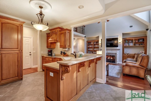 kitchen featuring hanging light fixtures, decorative columns, ornamental molding, black electric cooktop, and kitchen peninsula