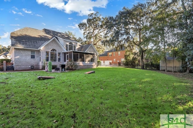 rear view of property featuring a sunroom and a lawn