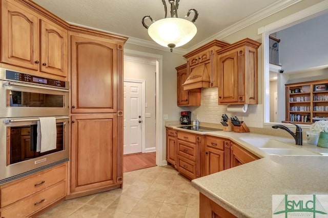 kitchen featuring sink, crown molding, pendant lighting, stainless steel double oven, and backsplash