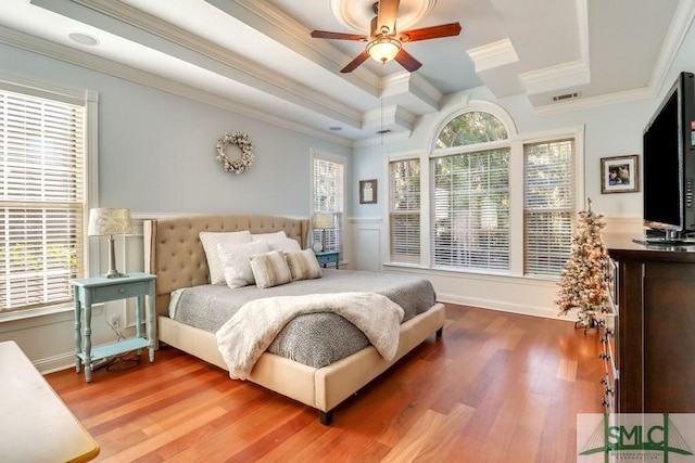 bedroom with multiple windows, crown molding, wood-type flooring, and a tray ceiling