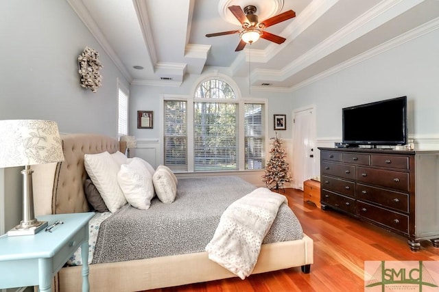 bedroom featuring a raised ceiling, ornamental molding, ceiling fan, and light hardwood / wood-style flooring