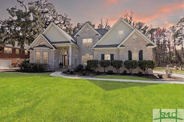 view of front of home with brick siding and a lawn