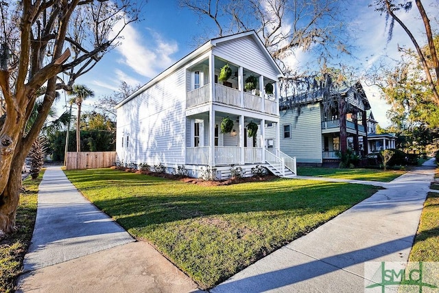 view of front of house featuring a front yard, a balcony, and covered porch