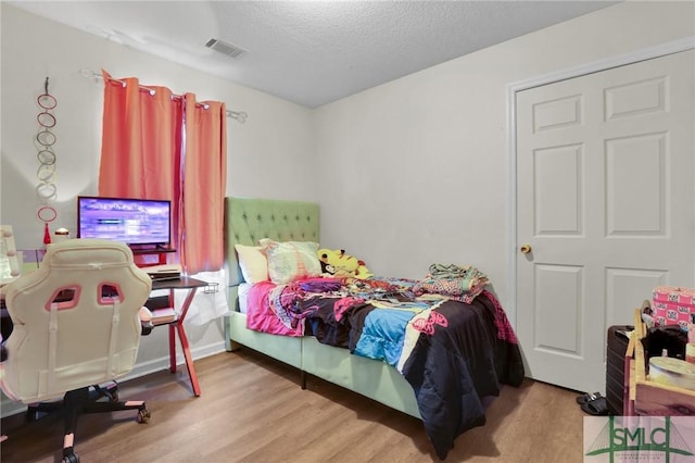 bedroom with light hardwood / wood-style floors and a textured ceiling